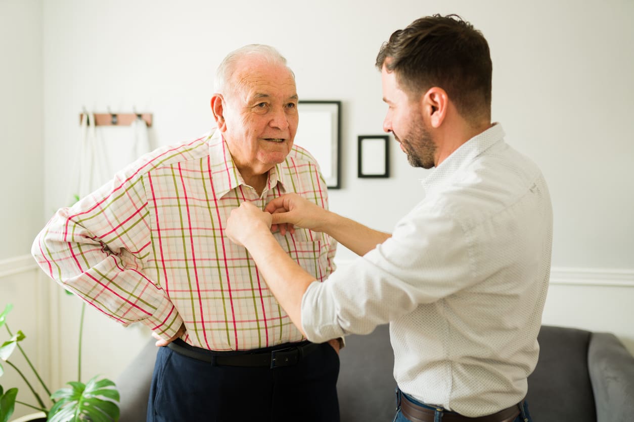 young man helping older man with shirt
