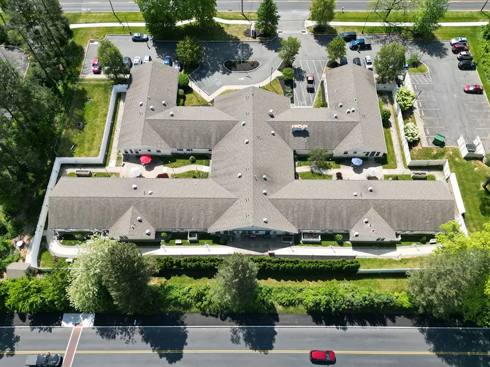 Allentown19 Aerial view of a large, single-story building with a cross-shaped roof, surrounded by trees, parking lots, and adjacent roads.