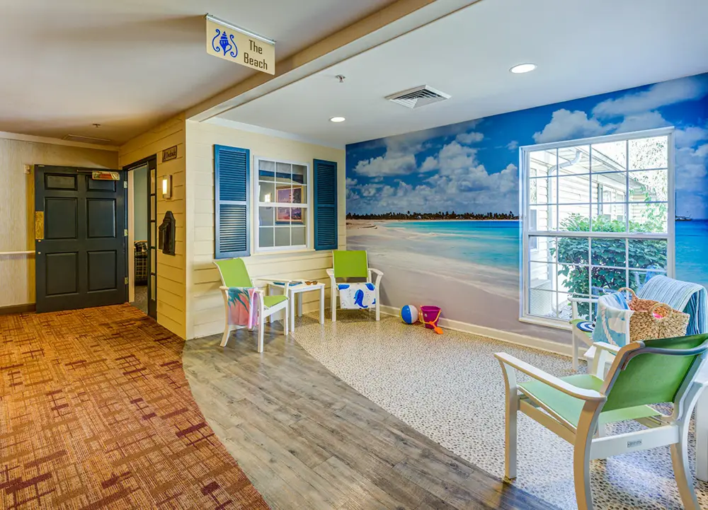 Allentown30 Indoor seating area decorated with beach-themed mural, window, chairs, and beach accessories; sign overhead reads "The Beach.
