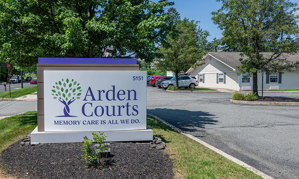 Allentown38 A sign for Arden Courts, a memory care facility, stands by a parking lot with several cars and trees near a single-story building.