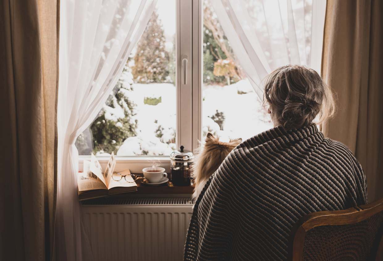 Cold Weather Concerns for Those Living with Alzheimers a woman enjoying a winter scene from inside