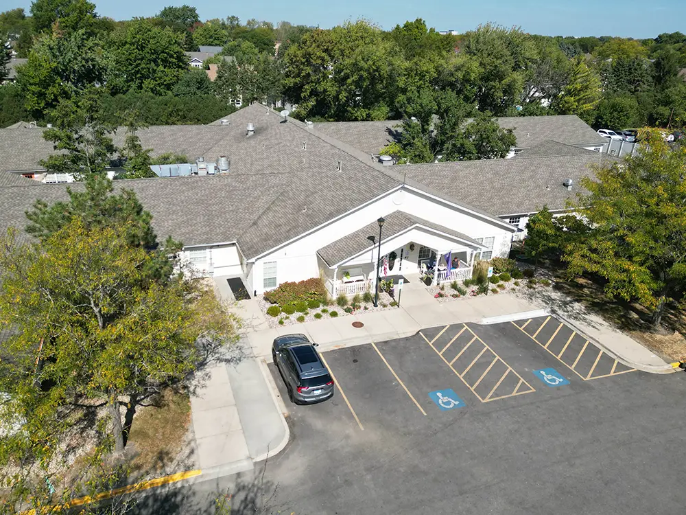 Elk Grove_-4 Aerial view of a single-story building with a parking lot containing one car and two accessible parking spaces, surrounded by trees.