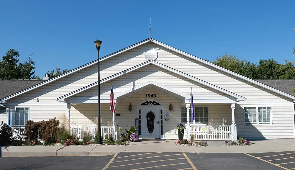 Elk Grove_-5 Single-story white building with a gabled roof, front porch, American flag, and accessible parking spaces in front, photographed on a clear, sunny day.
