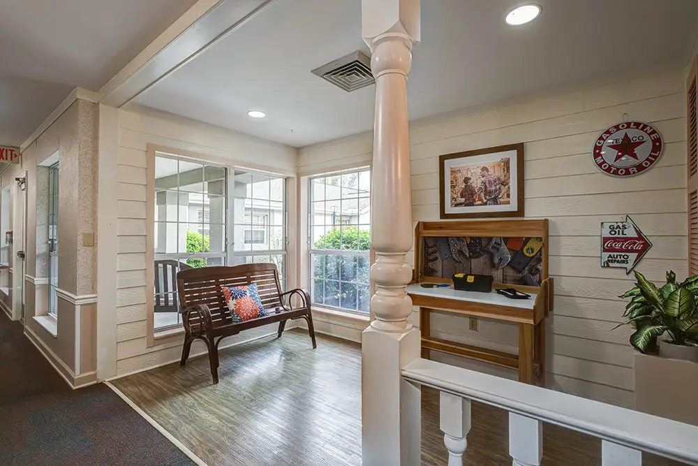 Indoor seating area with a wooden bench, side table, large windows, desk, wall art, Texaco sign, and Coca-Cola decor. Indoor seating area with a wooden bench, side table, large windows, desk, wall art, Texaco sign, and Coca-Cola decor.