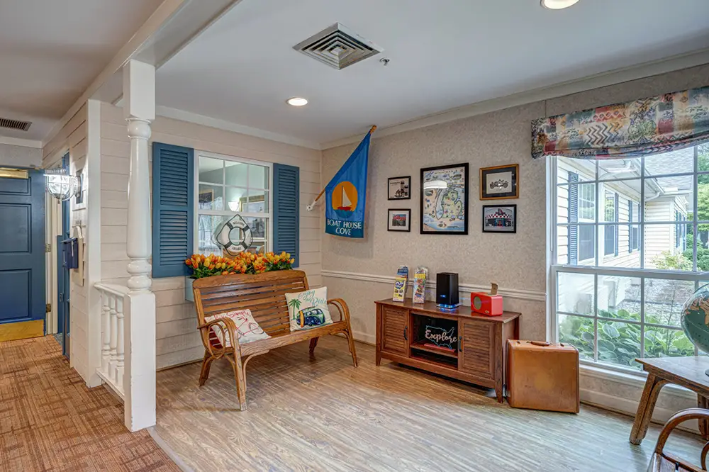 Cozy indoor seating area with a wooden bench, nautical decor, framed pictures on the wall, a blue flag, and a window letting in natural light.