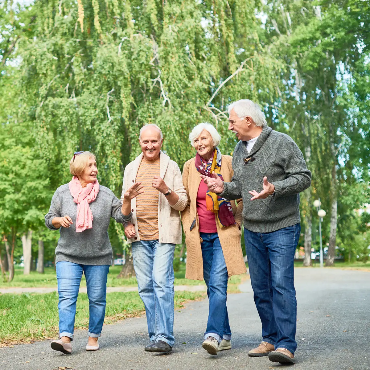 Older adults, smiling and walking together, with other people in the background.