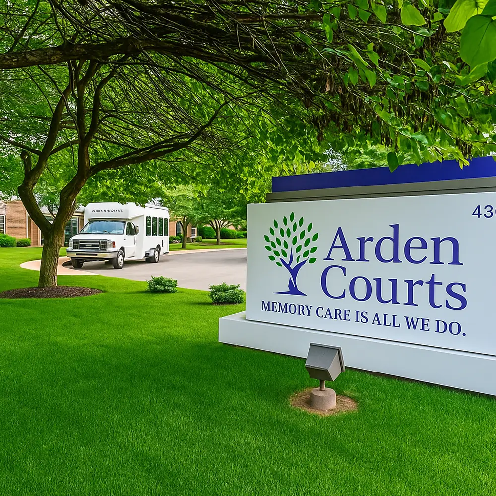 signs 2 A white shuttle bus drives past an Arden Courts sign that reads "Memory Care is All We Do" on a green, tree-lined property.